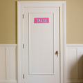 White door with a pink sign labeled 'SMASH' on a beige wall. PPQ rego plate