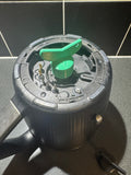 Black electric kettle top view with exposed heating element and green plastic knob on kitchen countertop