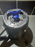 Black kitchen appliance lid with blue knob and metal prongs on countertop against black tiled wall