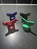 4 colorful 3D printed plastic clips in red, blue, green, and black on a dark countertop