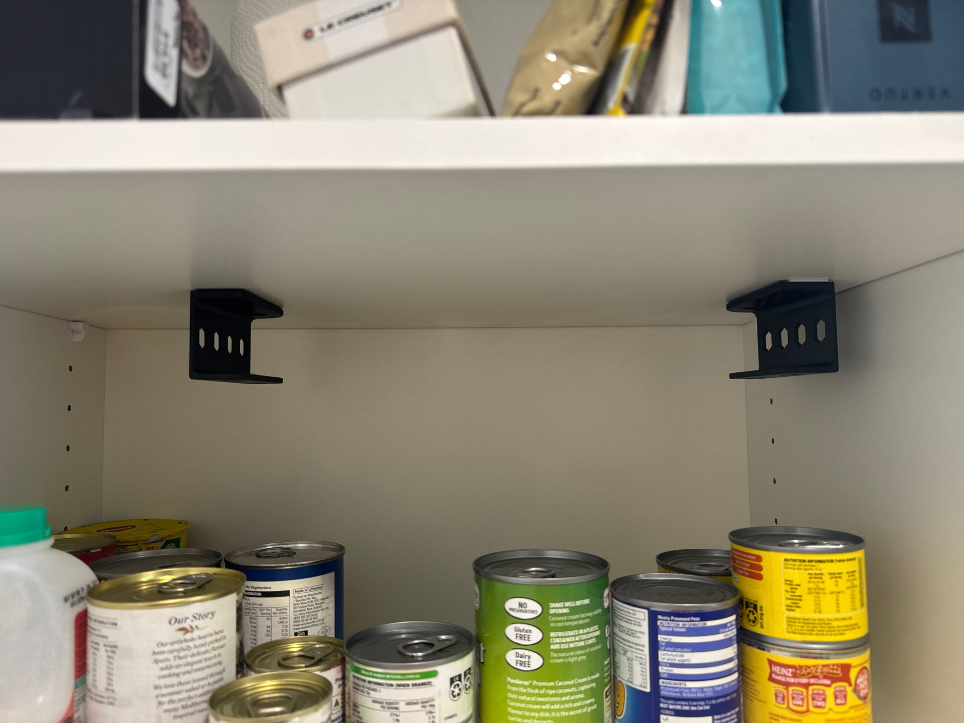 Canned goods on a pantry shelf with brackets visible