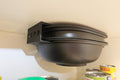 Varoma hanging from a hook on a beige wall with cans below.