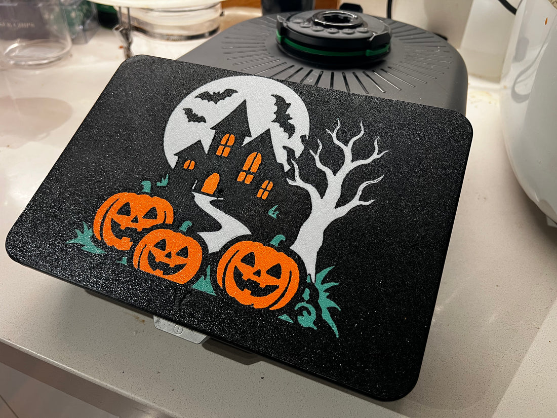 Haunted house Halloween screen cover on a Thermomix TM7 — full moon, crooked house with glowing orange windows, bats, bare tree and three jack-o'-lanterns