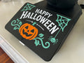 Happy Halloween spider web screen cover on a Thermomix TM7 — white lettering with teal webs, vines and a spider on black