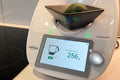 Vorwerk kitchen appliance with an avocado in a black bowl on a digital display showing weight.
